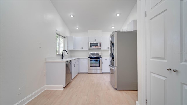 kitchen featuring lofted ceiling, sink, light hardwood / wood-style flooring, stainless steel appliances, and white cabinets