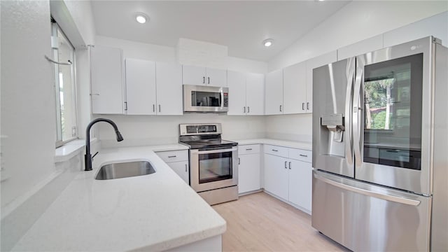 kitchen with sink, white cabinets, stainless steel appliances, and lofted ceiling