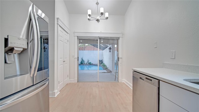 kitchen featuring appliances with stainless steel finishes, a notable chandelier, light hardwood / wood-style floors, and pendant lighting