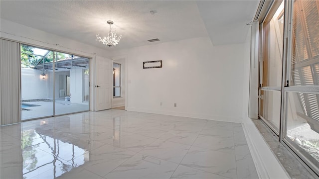 empty room featuring a textured ceiling and an inviting chandelier