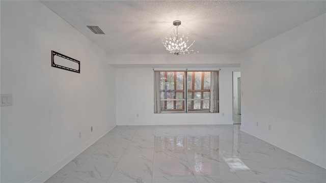 spare room featuring a textured ceiling and a chandelier