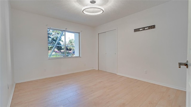 spare room with a textured ceiling and light hardwood / wood-style flooring