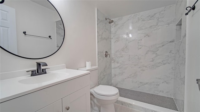 bathroom featuring toilet, vanity, and a tile shower