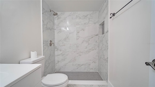 bathroom with toilet, vanity, and a tile shower