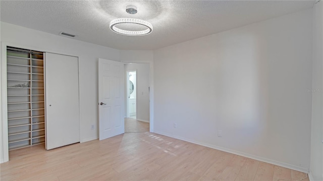 unfurnished bedroom featuring a textured ceiling, a closet, and light hardwood / wood-style floors