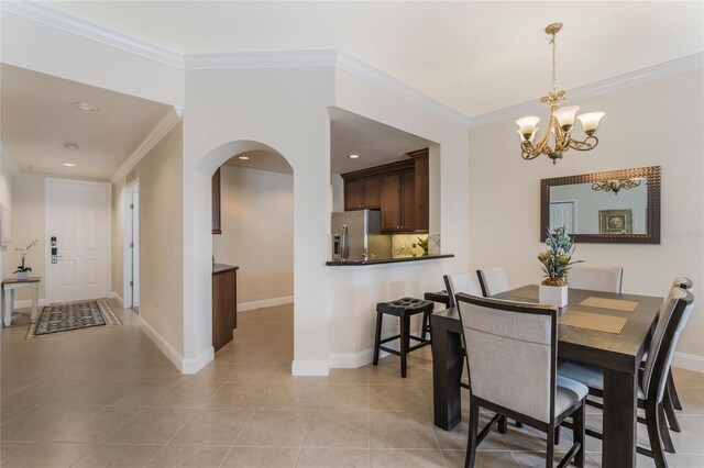 dining space featuring light tile patterned floors, crown molding, and a chandelier