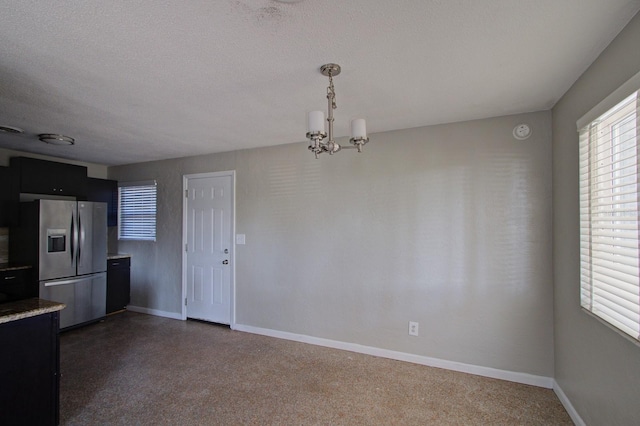 kitchen featuring a textured ceiling, an inviting chandelier, stainless steel fridge, and hanging light fixtures