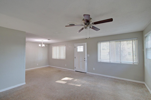 carpeted entrance foyer featuring ceiling fan with notable chandelier