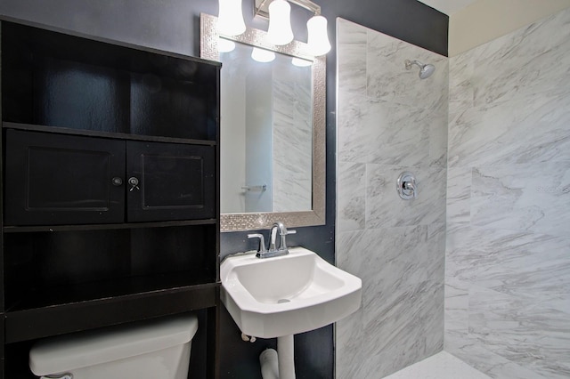 bathroom with toilet, sink, and tiled shower