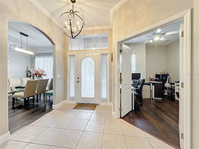 tiled entrance foyer featuring crown molding, plenty of natural light, and ceiling fan with notable chandelier