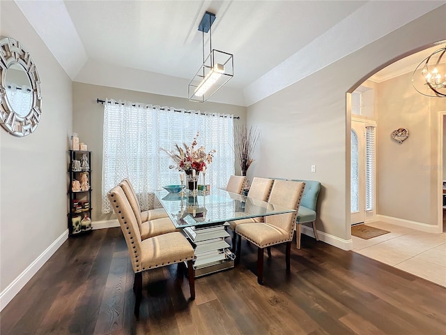 dining area with lofted ceiling, dark hardwood / wood-style flooring, and an inviting chandelier