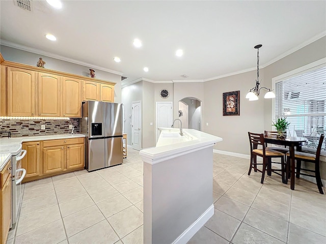 kitchen featuring light tile patterned flooring, crown molding, stainless steel fridge, an island with sink, and range with two ovens