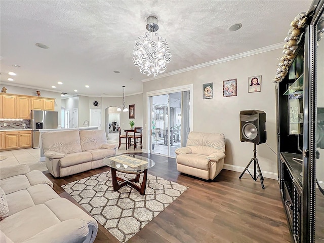 living room with crown molding, a textured ceiling, a chandelier, and light hardwood / wood-style floors