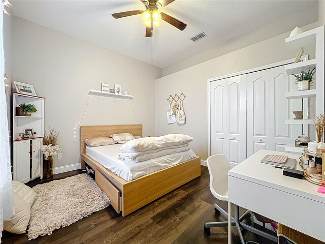 bedroom with dark wood-type flooring, ceiling fan, and a closet