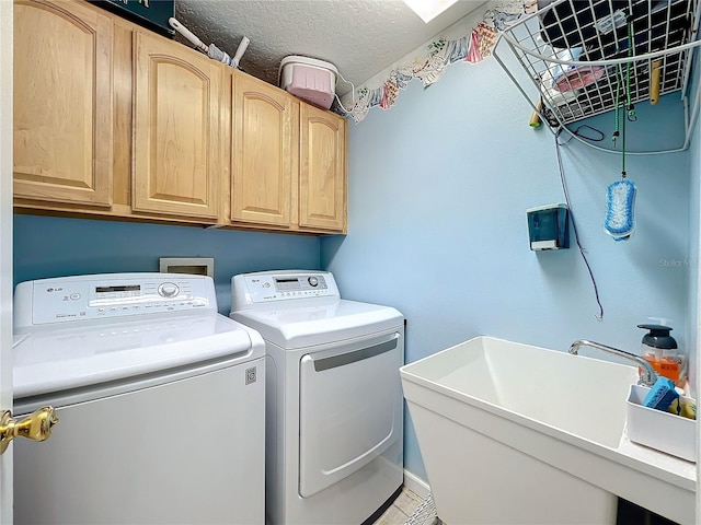 laundry area featuring cabinets, sink, washer and dryer, and a textured ceiling