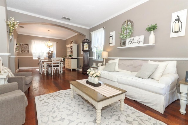 living room with crown molding, dark hardwood / wood-style floors, and an inviting chandelier