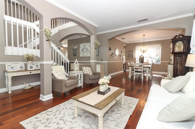 living room with dark hardwood / wood-style floors, crown molding, and an inviting chandelier