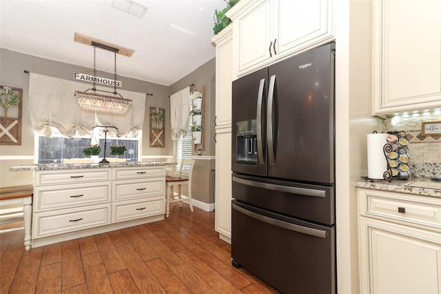 kitchen with tasteful backsplash, decorative light fixtures, hardwood / wood-style floors, light stone countertops, and stainless steel fridge with ice dispenser