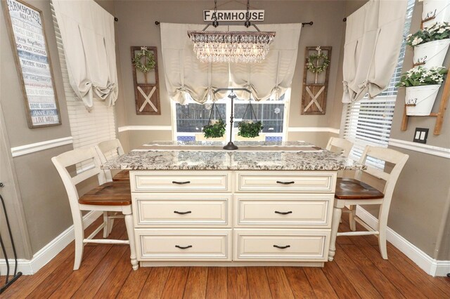 kitchen featuring decorative light fixtures, light stone counters, and hardwood / wood-style floors