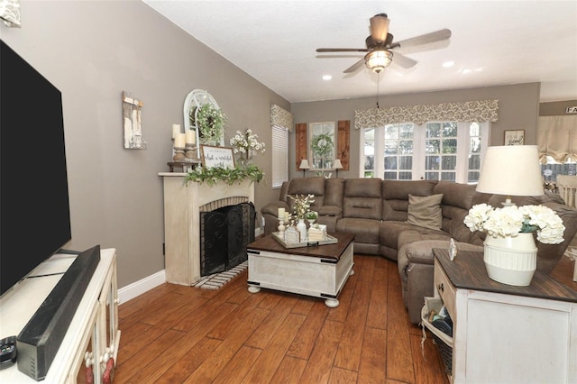 living room featuring ceiling fan and dark wood-type flooring