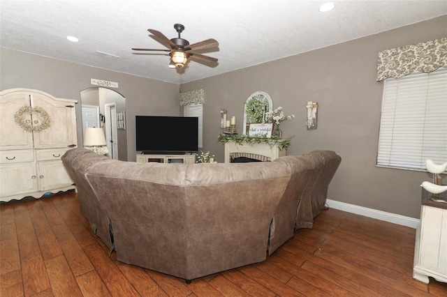 living room with ceiling fan, a textured ceiling, and dark hardwood / wood-style flooring