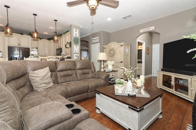 living room featuring ceiling fan and dark wood-type flooring