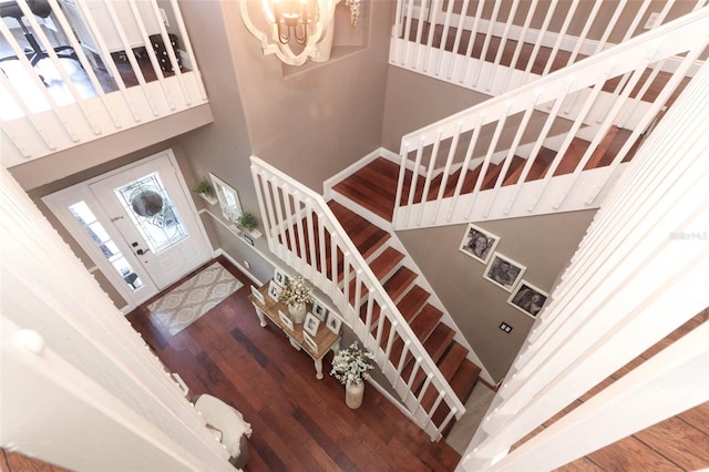 staircase featuring a notable chandelier, a high ceiling, and hardwood / wood-style floors