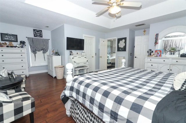 bedroom featuring ceiling fan, dark wood-type flooring, a tray ceiling, and a textured ceiling