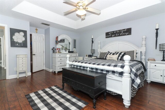 bedroom featuring ceiling fan, dark hardwood / wood-style flooring, and a raised ceiling