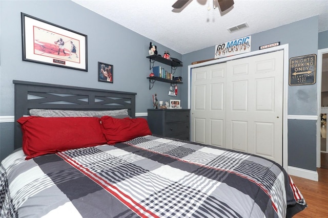 bedroom featuring ceiling fan, a textured ceiling, wood-type flooring, and a closet