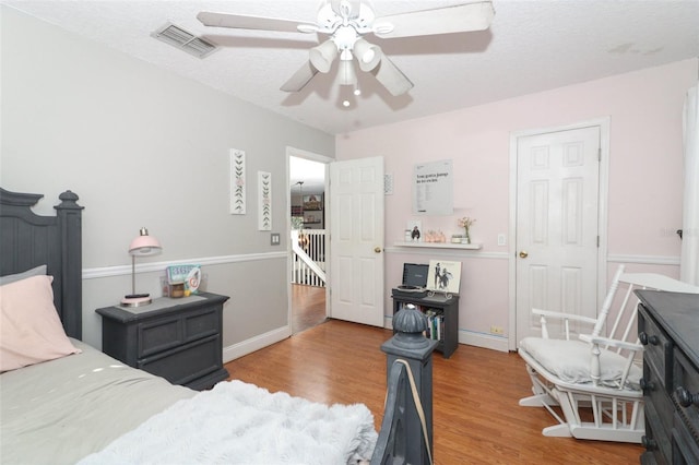 bedroom with ceiling fan, a textured ceiling, and hardwood / wood-style flooring