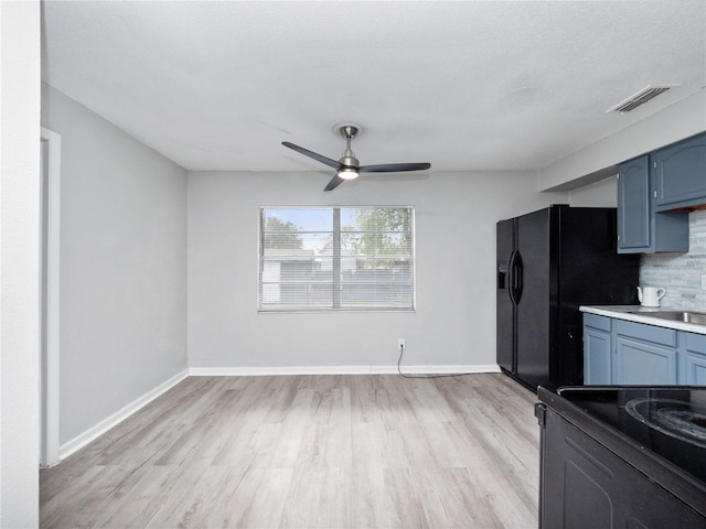 kitchen featuring electric stove, ceiling fan, black refrigerator with ice dispenser, light wood-type flooring, and blue cabinetry