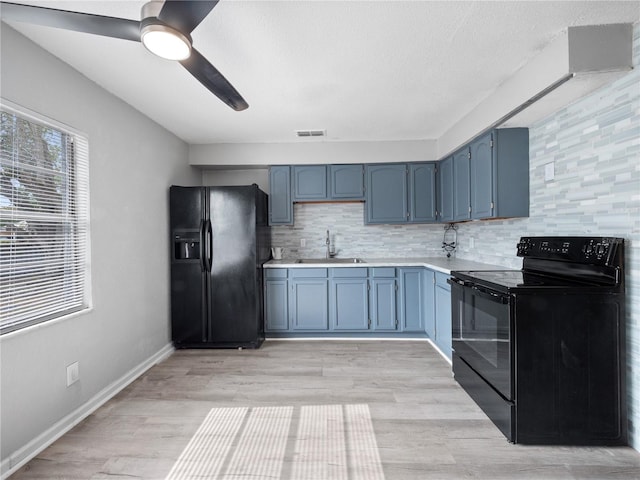 kitchen featuring black appliances, tasteful backsplash, sink, blue cabinetry, and ceiling fan