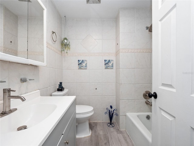 full bathroom with hardwood / wood-style floors, vanity, shower / bath combination, toilet, and tile walls