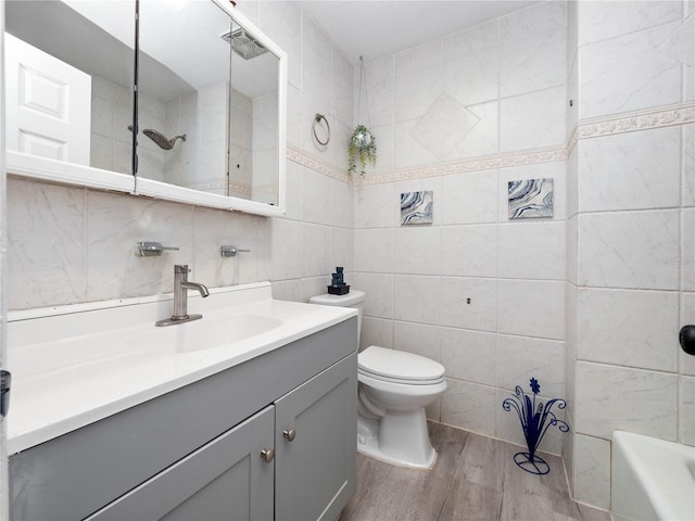 bathroom with toilet, vanity, tile walls, and wood-type flooring