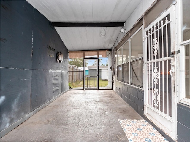 unfurnished sunroom featuring beam ceiling