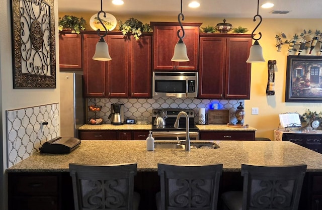 kitchen with sink, decorative light fixtures, stainless steel appliances, and a kitchen breakfast bar