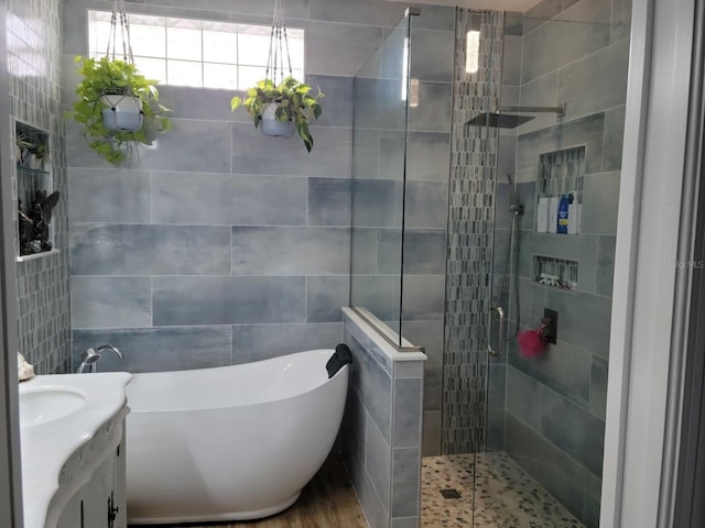 bathroom with independent shower and bath, vanity, and tile walls