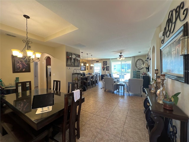 dining room with light tile patterned flooring, a raised ceiling, and ceiling fan with notable chandelier