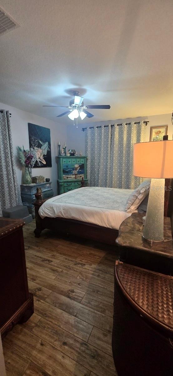 bedroom with dark hardwood / wood-style floors and ceiling fan