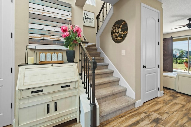 stairs with wood-type flooring and ceiling fan