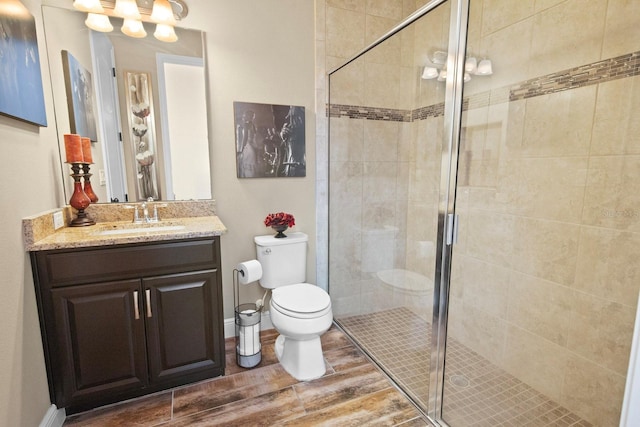 bathroom featuring vanity, toilet, and a shower with shower door