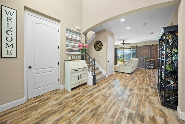 foyer with ceiling fan, a barn door, and light wood-type flooring