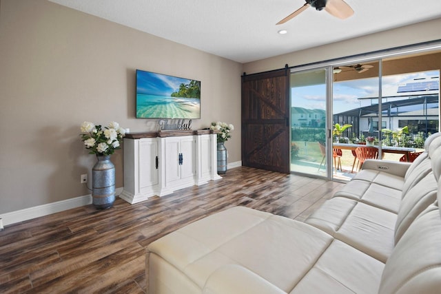 living room featuring hardwood / wood-style flooring, a barn door, and ceiling fan