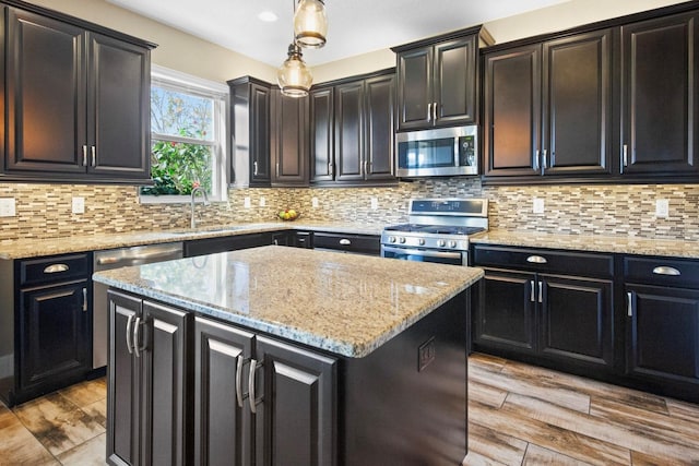 kitchen with pendant lighting, sink, backsplash, a center island, and stainless steel appliances