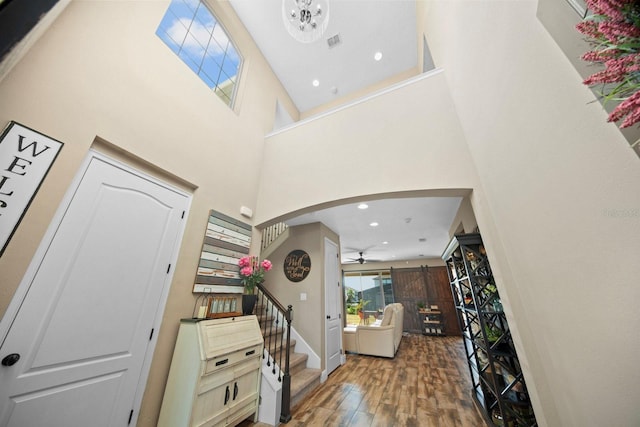 entryway with hardwood / wood-style flooring, ceiling fan, and a high ceiling