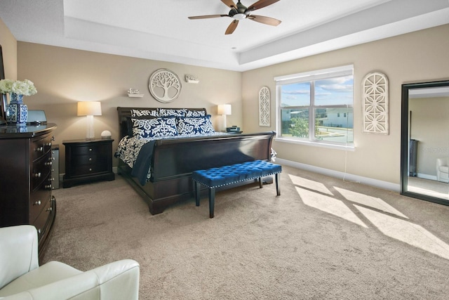 bedroom with ceiling fan, a tray ceiling, and carpet floors