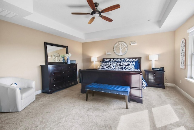 carpeted bedroom featuring ceiling fan and a tray ceiling