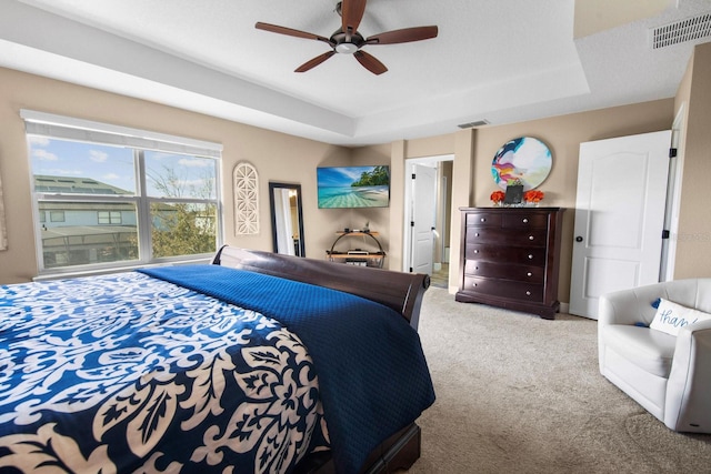 bedroom with ceiling fan, a raised ceiling, and light carpet