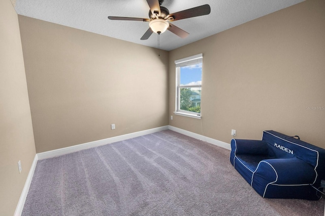 sitting room with ceiling fan, carpet flooring, and a textured ceiling